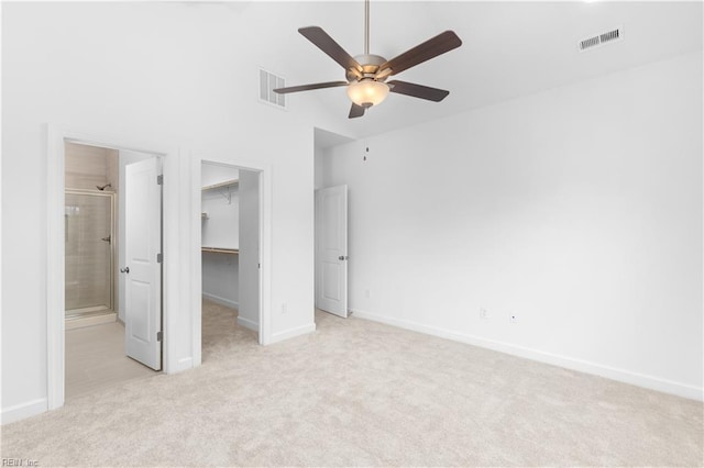 unfurnished bedroom with a walk in closet, visible vents, a closet, and light carpet