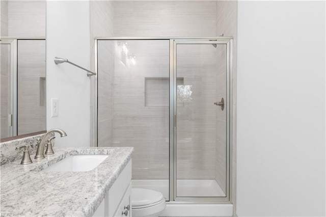 bathroom with a stall shower, toilet, and vanity