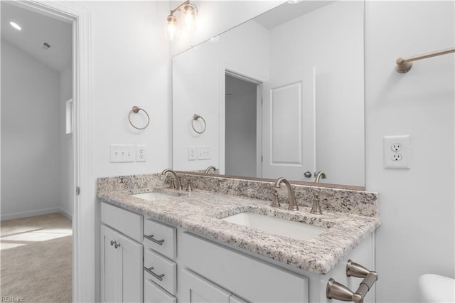 bathroom featuring a sink, baseboards, toilet, and double vanity