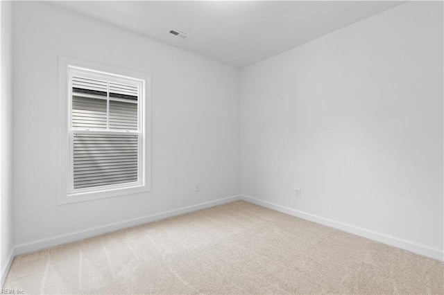 carpeted spare room with visible vents and baseboards