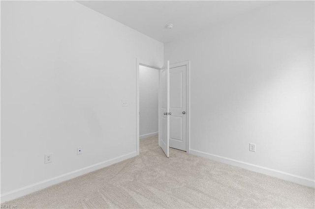 empty room featuring light colored carpet and baseboards