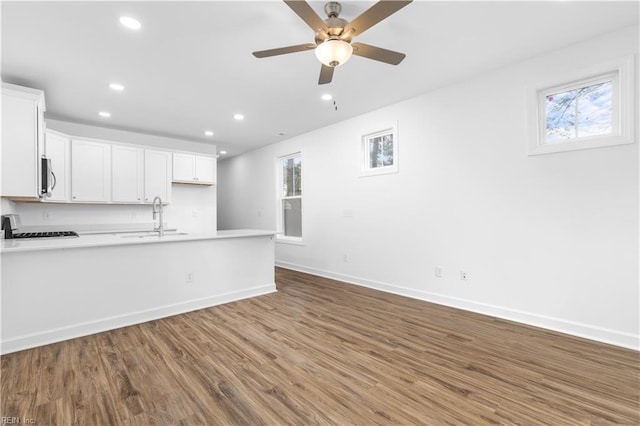 kitchen with a sink, wood finished floors, recessed lighting, a peninsula, and range