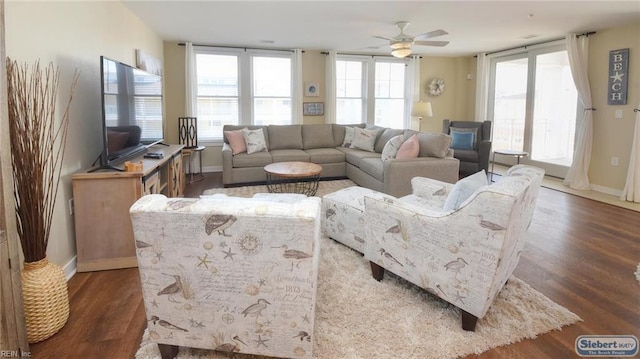 living room featuring ceiling fan, baseboards, and wood finished floors