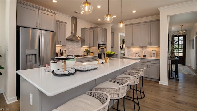 kitchen featuring stainless steel appliances, gray cabinetry, ornamental molding, and wall chimney exhaust hood