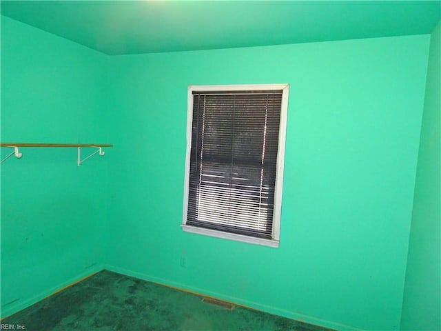 unfurnished room featuring carpet flooring, visible vents, and baseboards