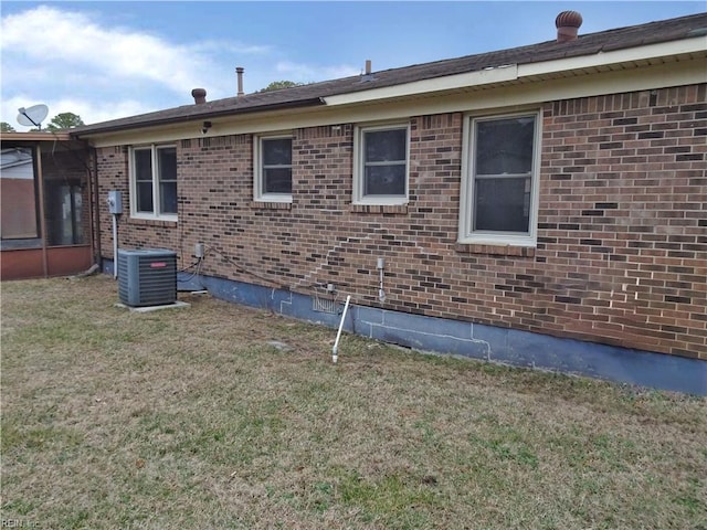 view of property exterior featuring brick siding, a lawn, and central air condition unit