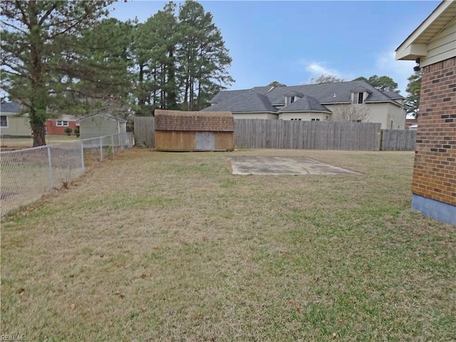 view of yard featuring an outbuilding, a patio, a storage unit, and a fenced backyard