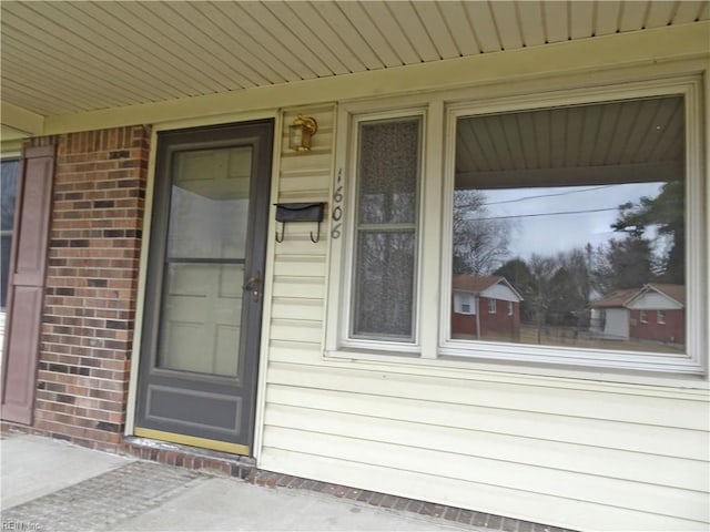 property entrance featuring brick siding and a porch