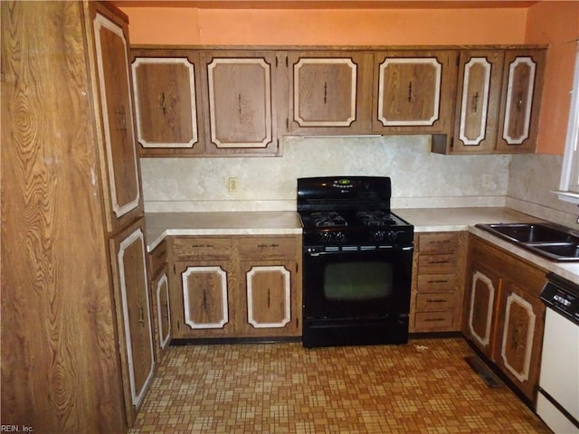 kitchen with white dishwasher, black range with gas stovetop, a sink, and brown cabinetry