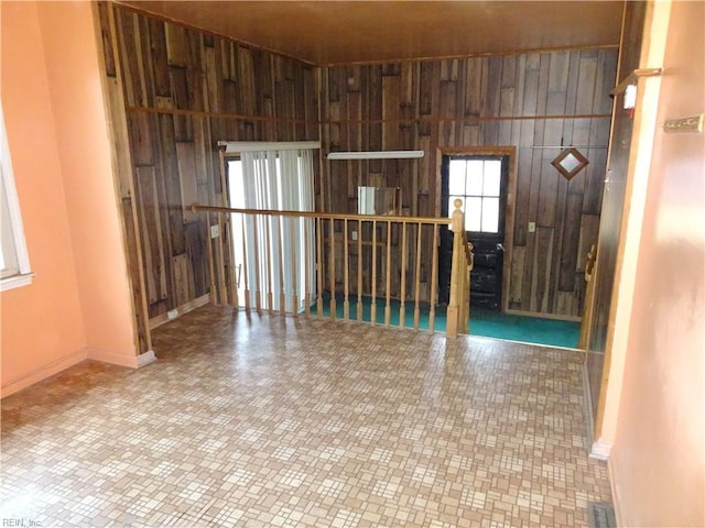 unfurnished room with wood walls, visible vents, and baseboards