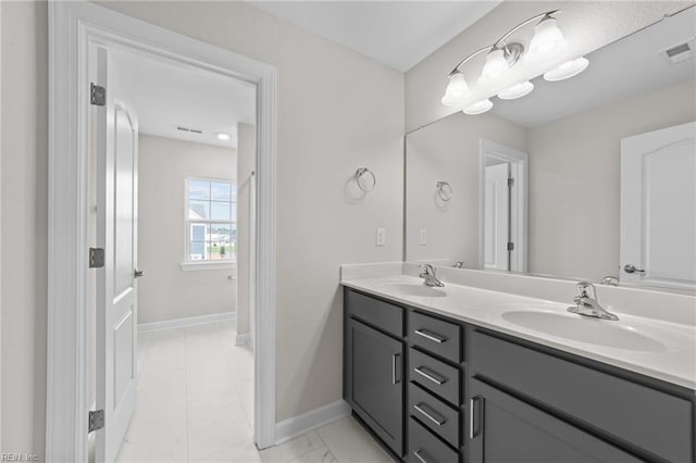 bathroom with double vanity, baseboards, visible vents, and a sink