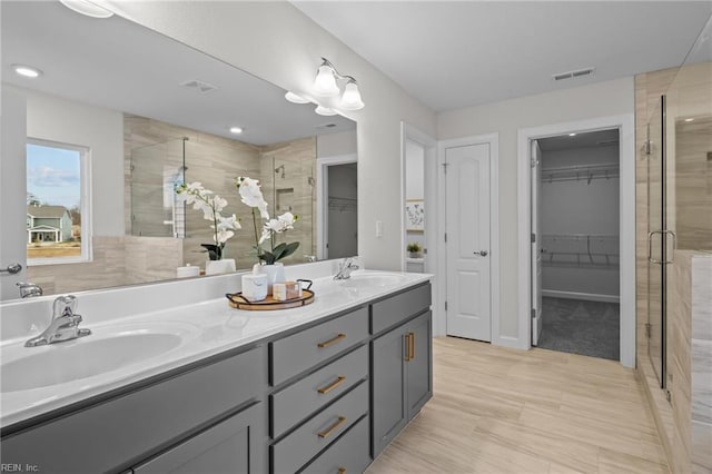 bathroom with a stall shower, a sink, visible vents, and a walk in closet