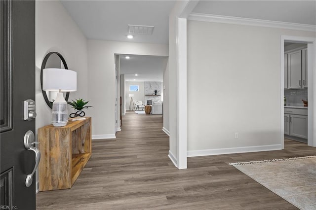 foyer entrance with crown molding, wood finished floors, visible vents, and baseboards