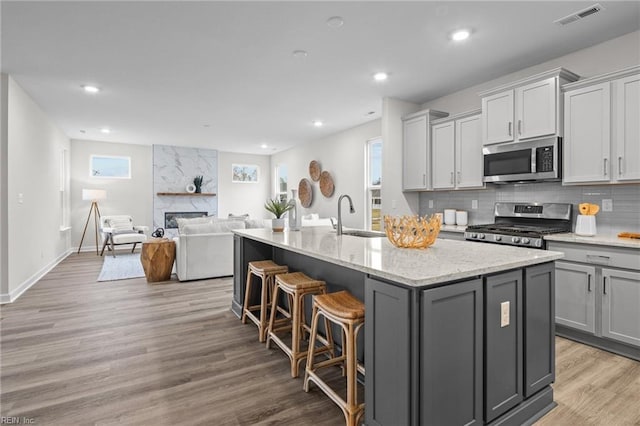 kitchen featuring stainless steel appliances, a sink, visible vents, gray cabinets, and tasteful backsplash