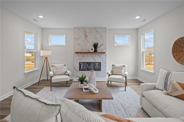 living room featuring visible vents, a fireplace, baseboards, and wood finished floors