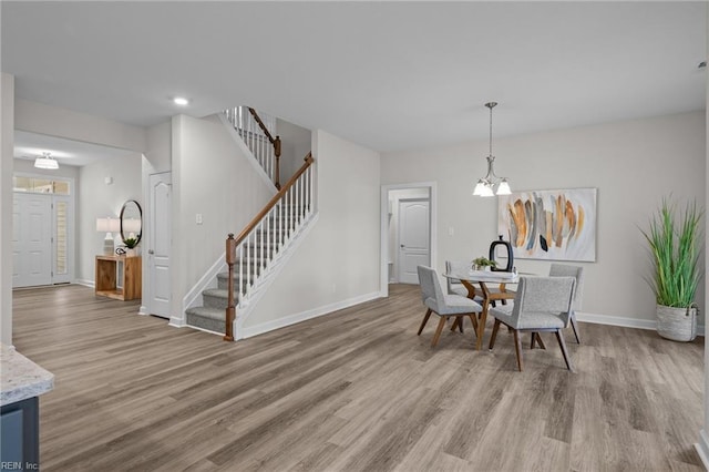 dining room with baseboards, a notable chandelier, stairway, and wood finished floors