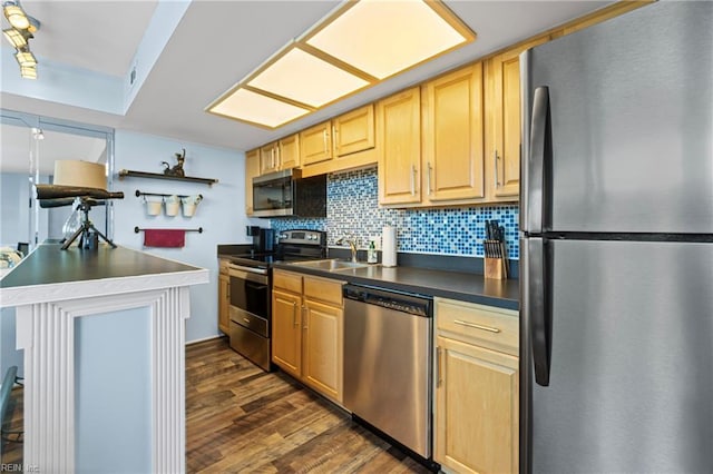 kitchen featuring dark wood-type flooring, light brown cabinetry, dark countertops, tasteful backsplash, and appliances with stainless steel finishes