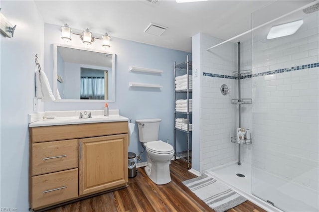 bathroom featuring toilet, tiled shower, and wood finished floors