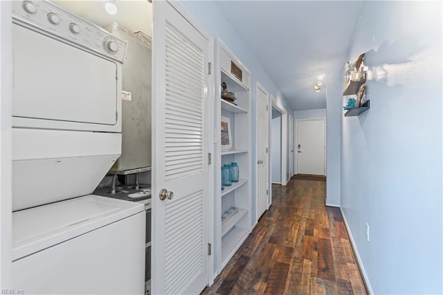 clothes washing area with dark wood finished floors, laundry area, baseboards, and stacked washer and dryer