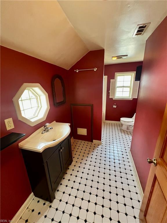 bathroom featuring visible vents, toilet, lofted ceiling, tile patterned floors, and vanity