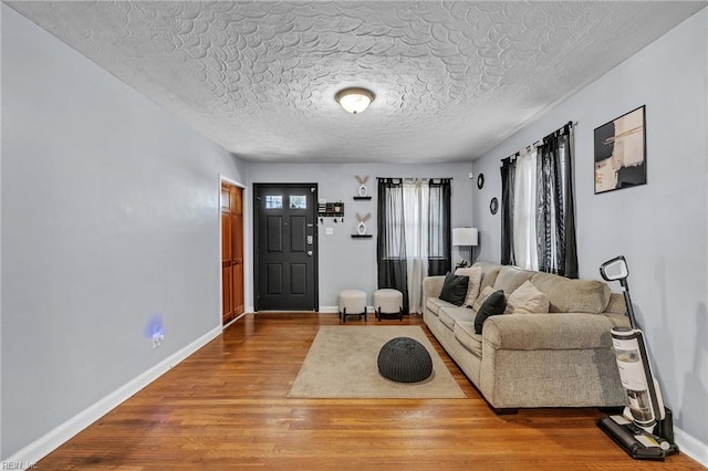 living area featuring a textured ceiling, baseboards, and wood finished floors