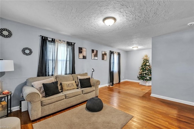 living area featuring a textured ceiling, wood finished floors, and baseboards