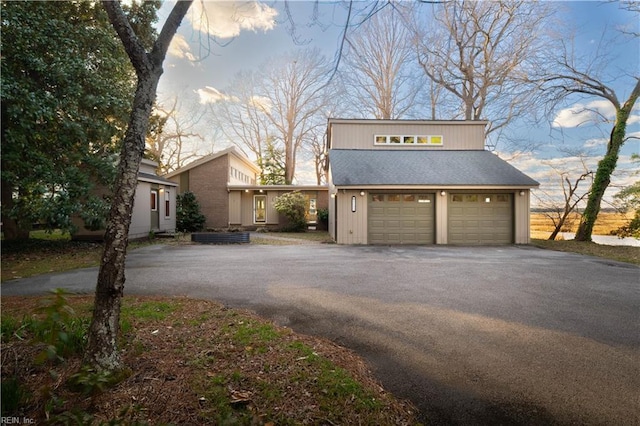 view of side of home featuring a garage, driveway, and roof with shingles