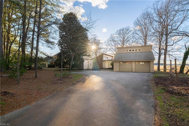 view of front of property with a garage, roof with shingles, and driveway