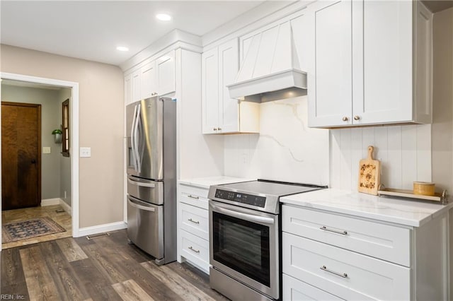 kitchen with dark wood-style floors, white cabinetry, stainless steel appliances, light stone countertops, and custom exhaust hood