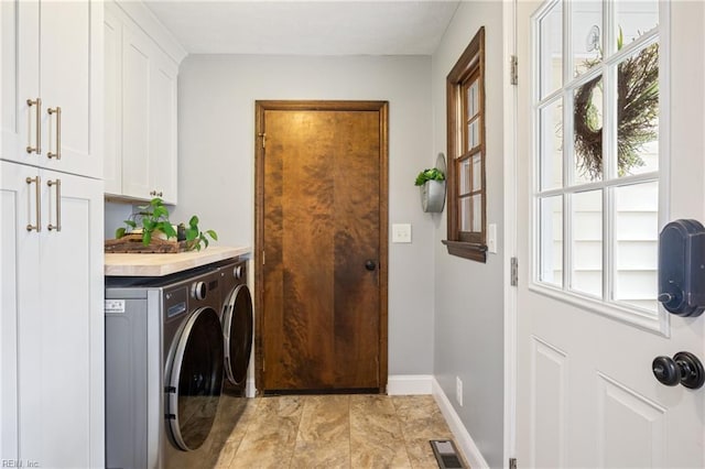 washroom with visible vents, cabinet space, baseboards, and washing machine and dryer