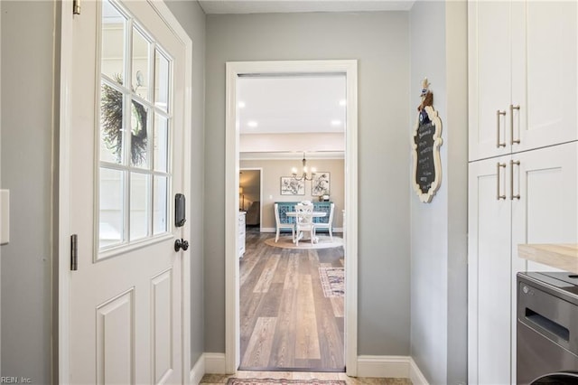 doorway with baseboards, washer / clothes dryer, an inviting chandelier, and light wood-style flooring