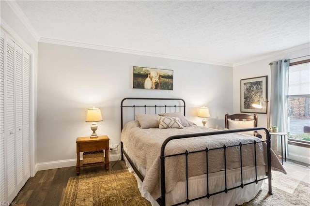 bedroom with a closet, crown molding, baseboards, and wood finished floors