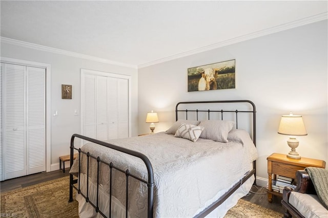 bedroom featuring crown molding, wood finished floors, baseboards, and two closets