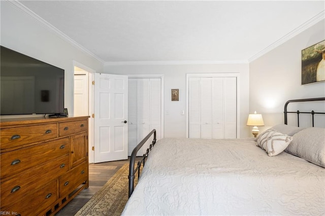 bedroom featuring two closets, dark wood-style flooring, and crown molding