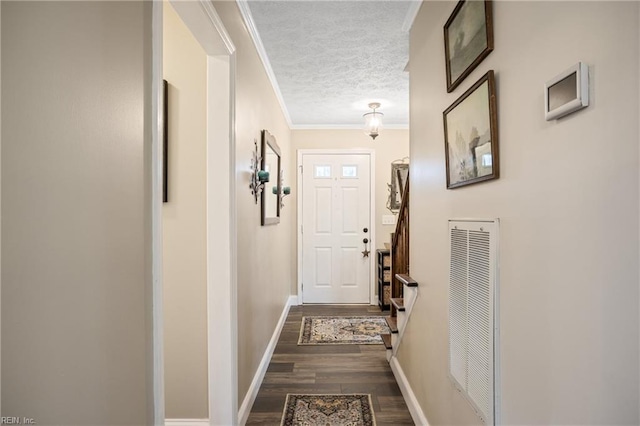 entryway featuring visible vents, crown molding, baseboards, dark wood finished floors, and a textured ceiling