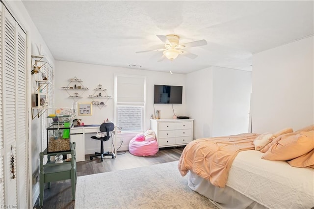 bedroom with a textured ceiling, a ceiling fan, and wood finished floors