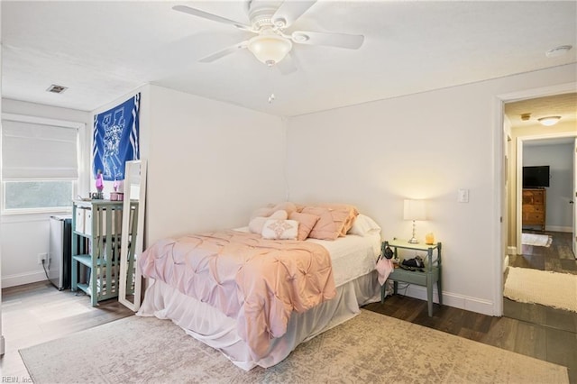 bedroom featuring ceiling fan, wood finished floors, visible vents, and baseboards