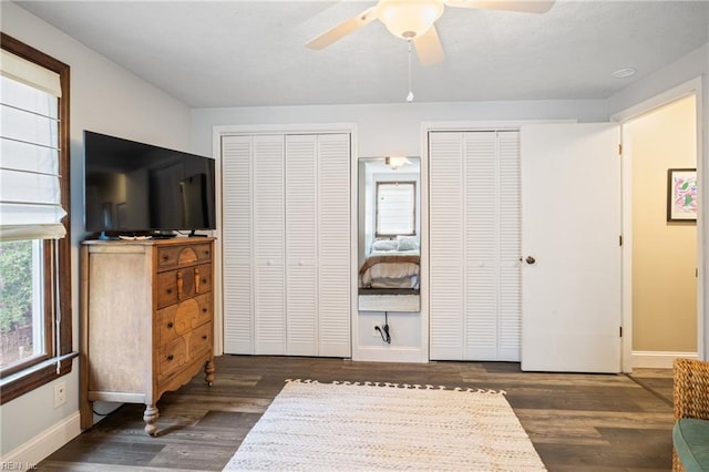 bedroom featuring ceiling fan, baseboards, multiple closets, and wood finished floors