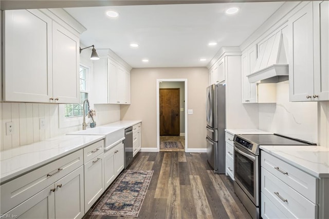 kitchen featuring dark wood-type flooring, appliances with stainless steel finishes, custom exhaust hood, white cabinets, and a sink