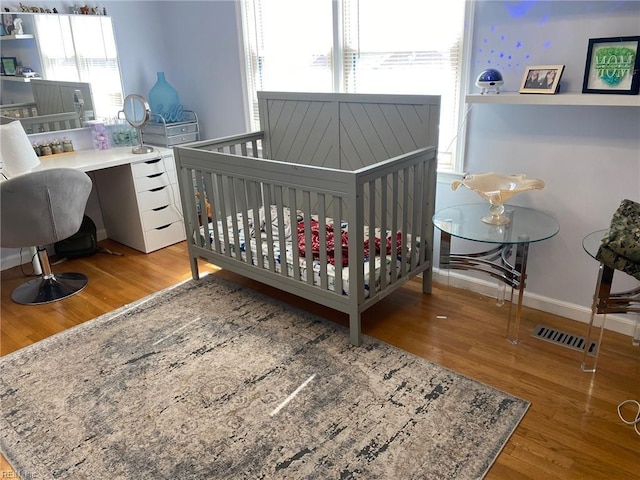 bedroom with multiple windows, wood finished floors, and visible vents