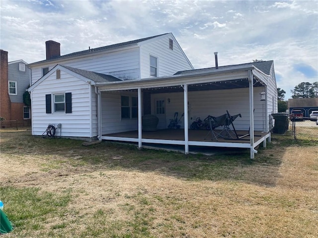 rear view of property featuring a yard, fence, and a chimney