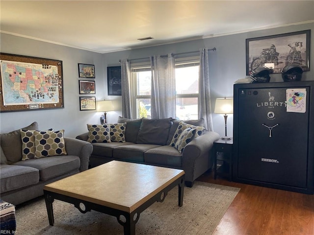 living room with visible vents, wood finished floors, and ornamental molding