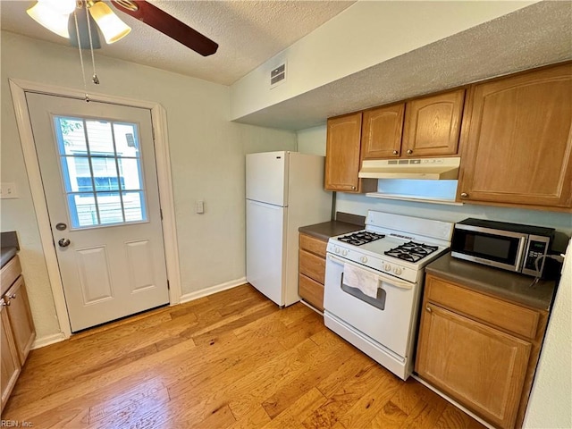 kitchen with white appliances, light wood-style floors, visible vents, and under cabinet range hood