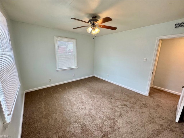 carpeted spare room with a ceiling fan, visible vents, and baseboards