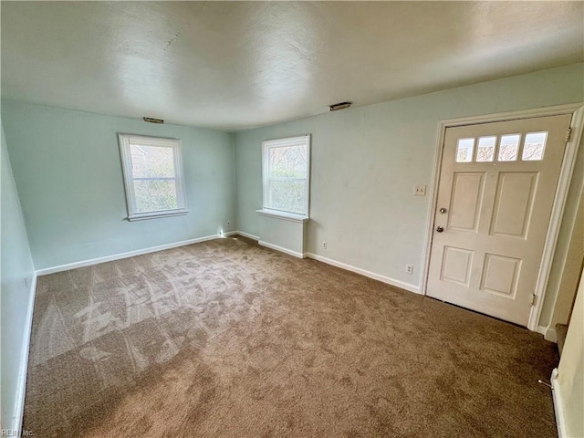 carpeted foyer featuring baseboards