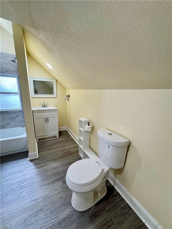 full bathroom with a textured ceiling, a tub to relax in, wood finished floors, and toilet