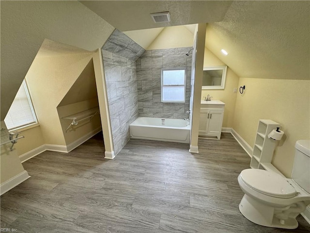 full bathroom featuring a textured ceiling, toilet, wood finished floors, visible vents, and washtub / shower combination