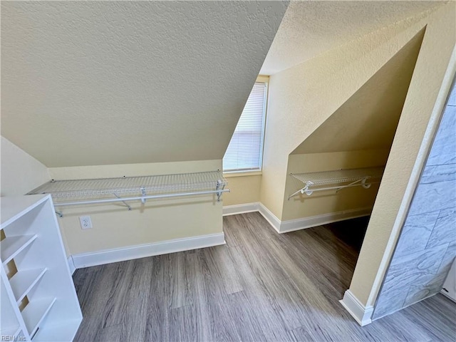 additional living space featuring a textured ceiling, baseboards, and wood finished floors