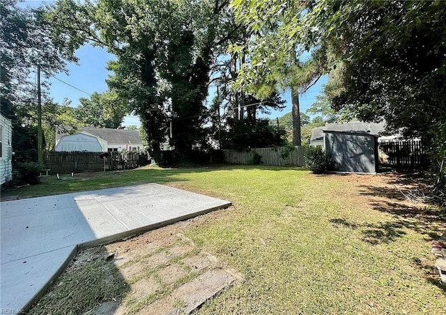 view of yard featuring an outbuilding, a patio, a storage shed, and a fenced backyard