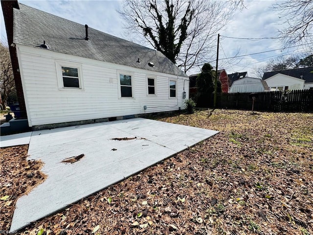 rear view of property featuring a shingled roof, a patio area, and fence